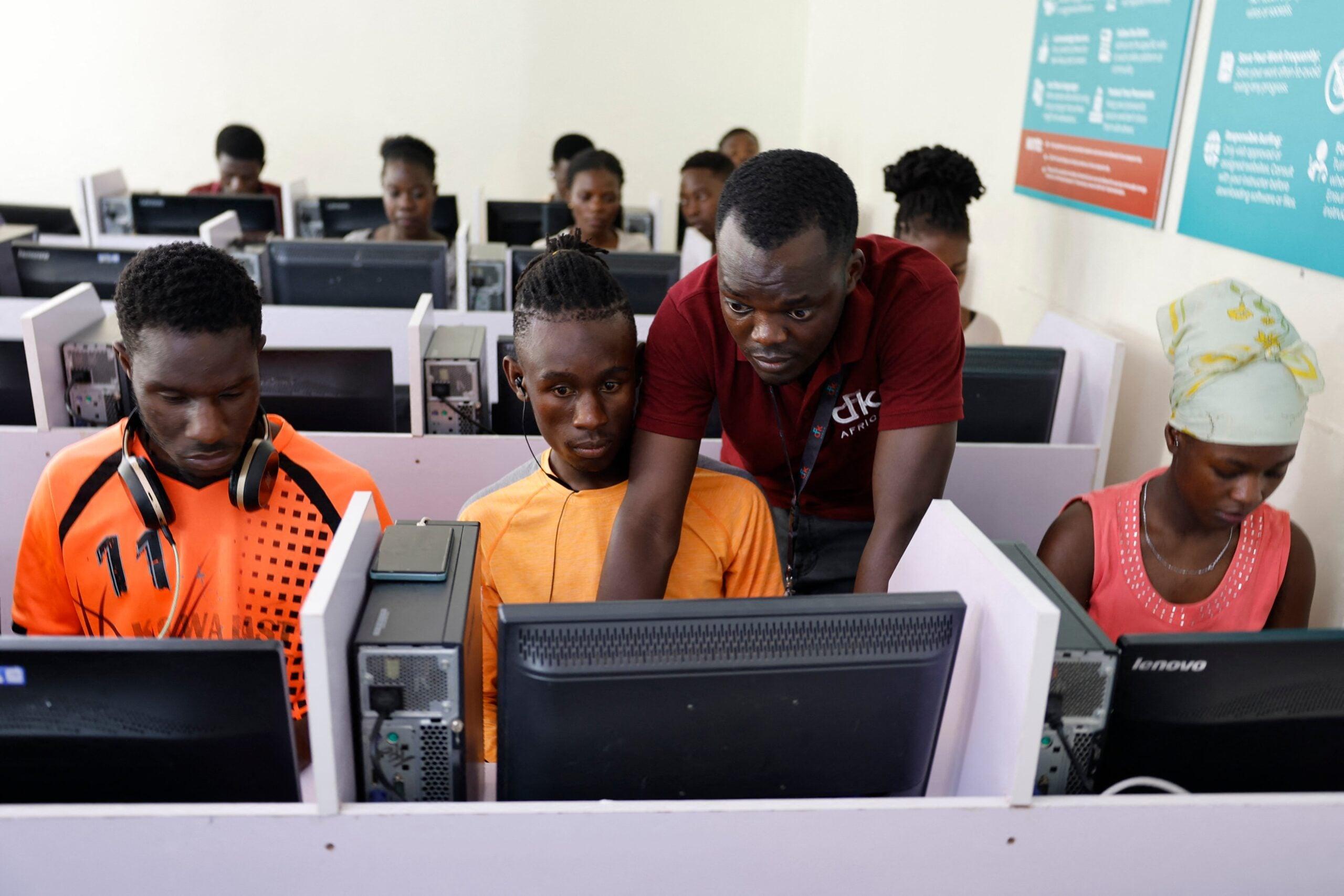 Students working together at computer stations with an instructor providing guidance