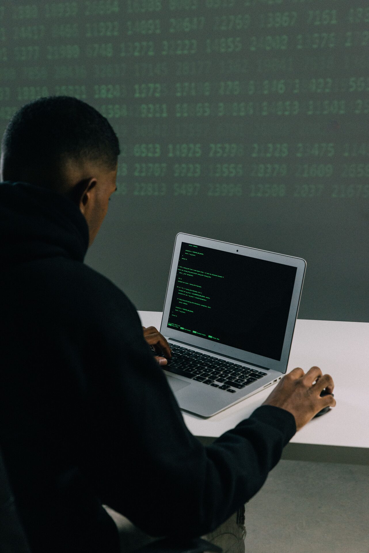 Student working at a laptop with live security data displayed behind them