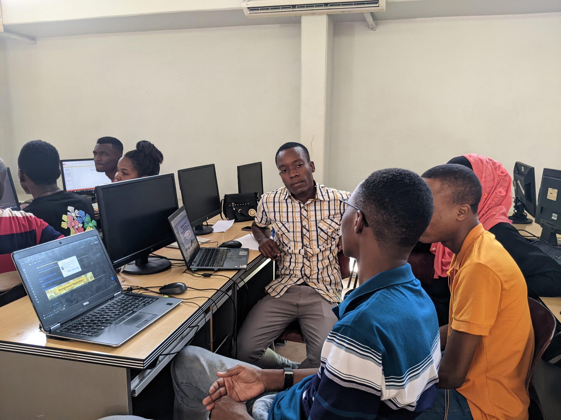 Students working together at computers with a mentor guiding one learner